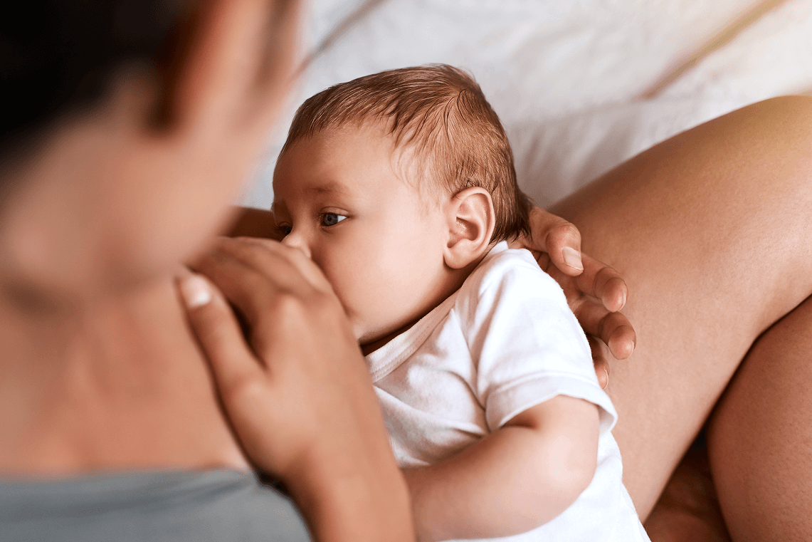 Madre che allatta al seno il suo neonato tenendolo dolcemente tra le braccia.