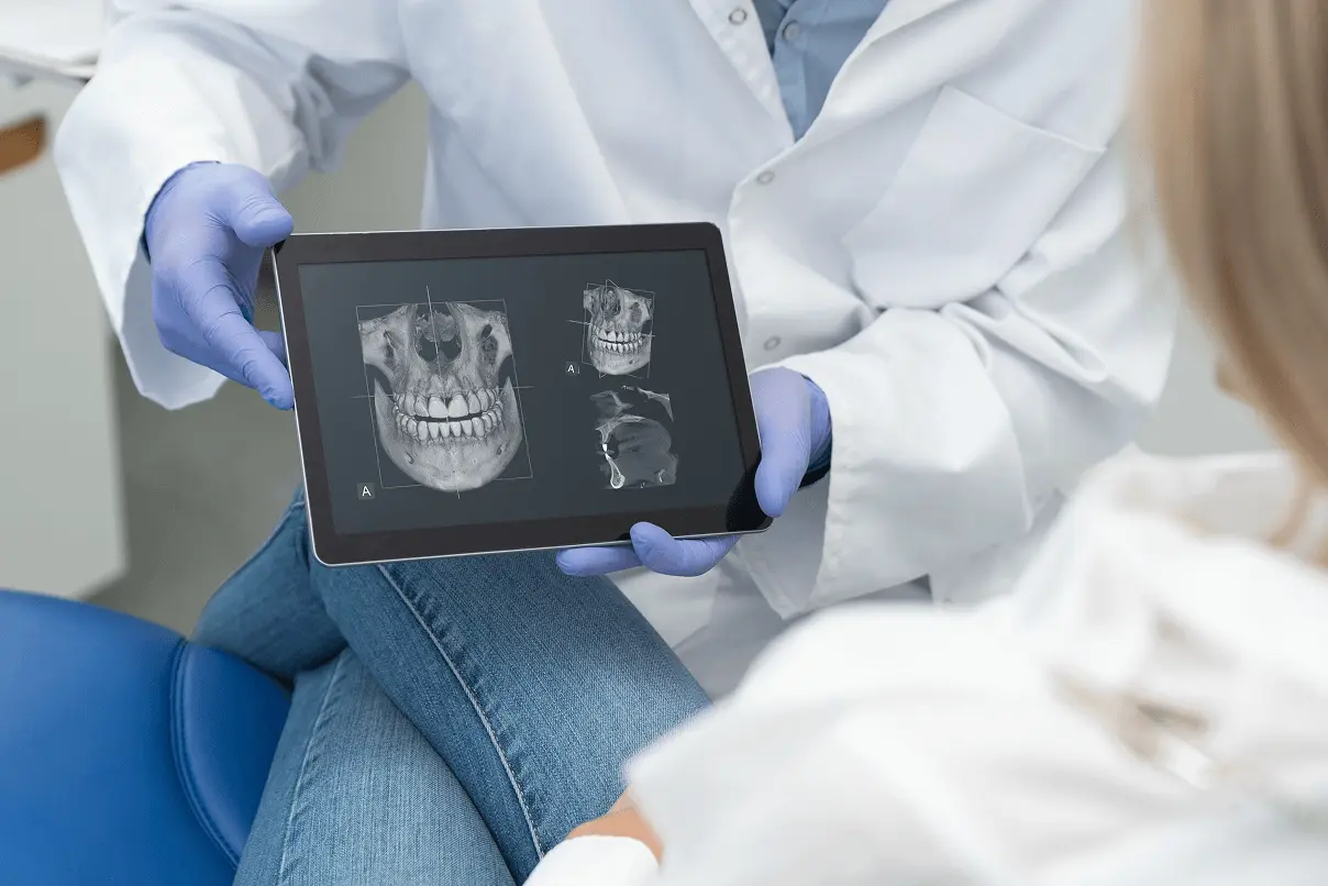 Spiegazione del piano di cura tramite immagini TAC Cone Beam 3D sul display di un tablet per valutare la struttura ossea e le arcate dentarie.