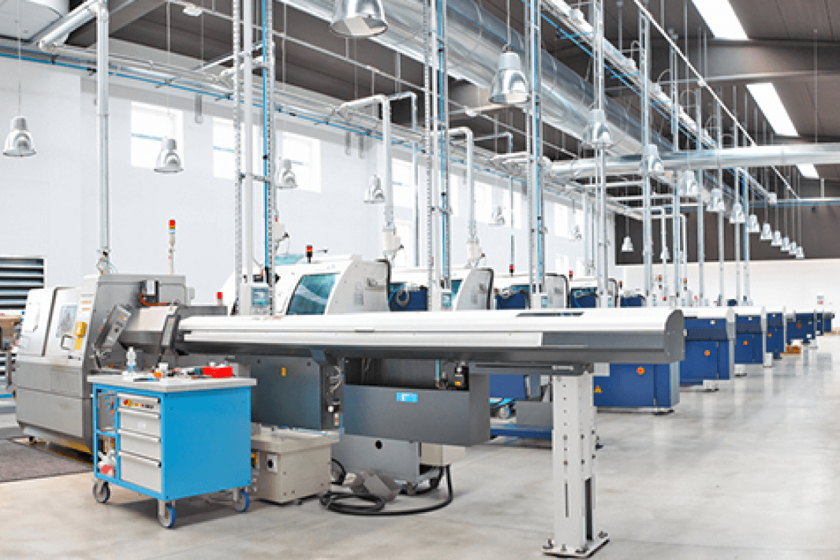 Vista interna di un moderno ed luminoso capannone industriale con una fila di torni e macchine a controllo numerico (CNC).