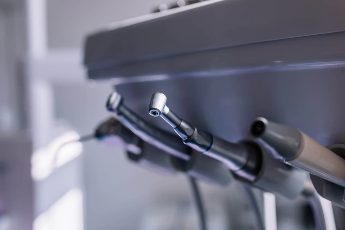 Dettaglio in primo piano dei manipoli e delle turbine odontoiatriche posizionati sul supporto del riunito dentistico.